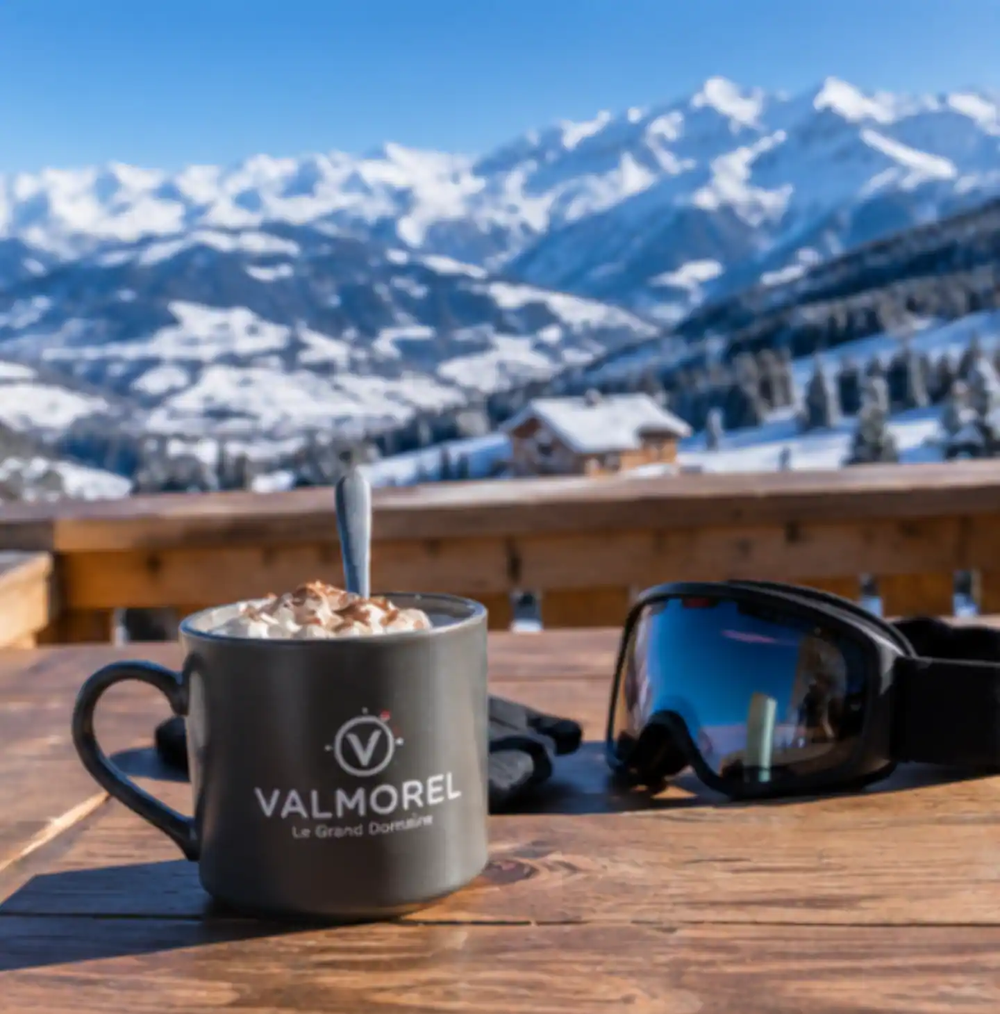 Chocolat chaud et masque de ski sur la terrasse, vue sur les sommets enneigés